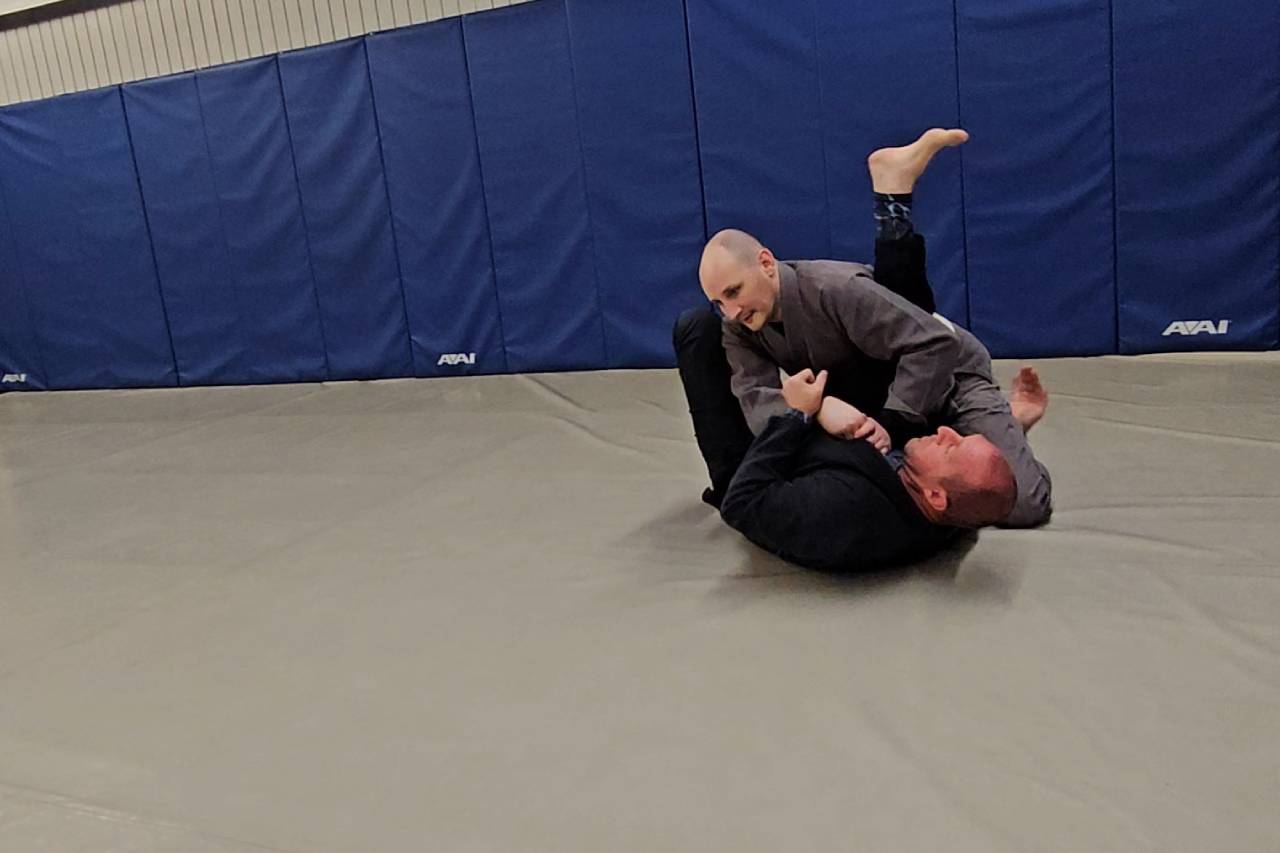 Two individuals practicing Brazilian Jiu-Jitsu on a mat. Two individuals practicing Brazilian Jiu-Jitsu on a mat.